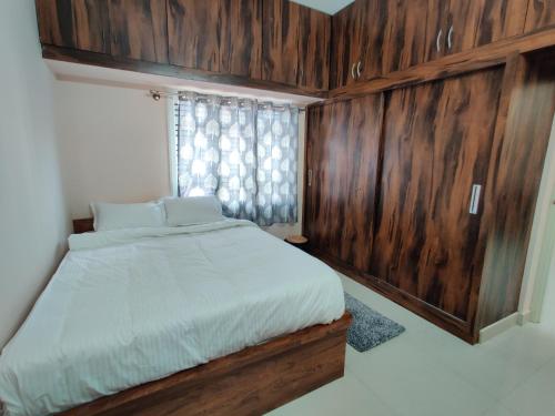 a bedroom with a bed with wooden walls and a window at SV Serviced Apartments in Chikmagalūr