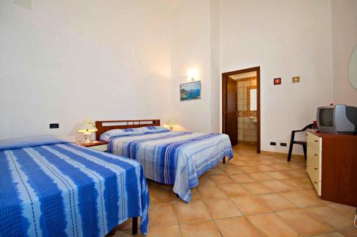 a hotel room with two beds and a television at Blunda Holiday Home in Castellammare del Golfo