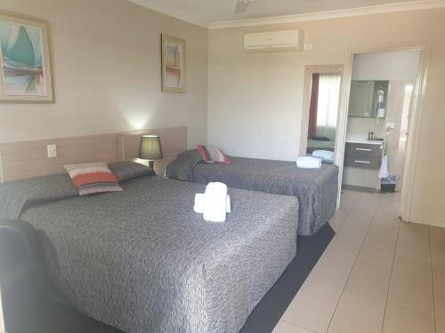 a hotel room with two beds and a bathroom at Cobar Central Motor Inn in Cobar