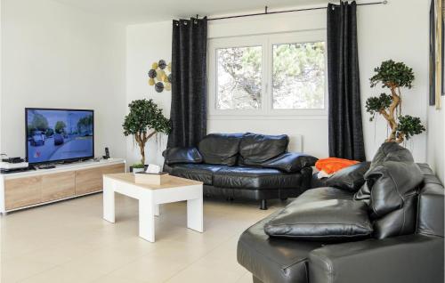 ein Wohnzimmer mit schwarzen Ledermöbeln und einem Flachbildfernseher in der Unterkunft Lovely Home In Saint-Germain-Sur-Ay in Saint-Germain-sur-Ay