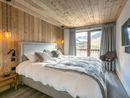 une chambre avec un grand lit avec un plafond en bois dans l'établissement Appartement de luxe avec cheminée, balcon et services inclus, au pied de la forêt de Bellevarde - FR-1-694-12, à Val dʼIsère