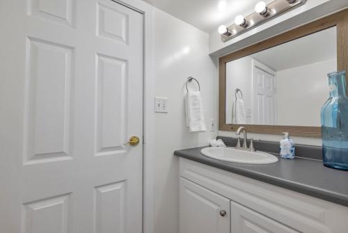 a white bathroom with a sink and a mirror at Quaint 1 bedroom lower suite in Victoria, BC in Victoria