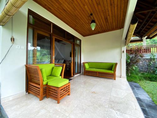a patio with two green chairs on a porch at Lesong Hotel and Restaurant in Munduk