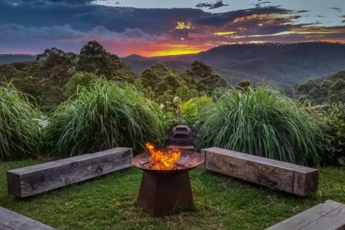 eine Feuerstelle im Gras mit Sonnenuntergang in den Bergen in der Unterkunft Mountain View Escape in Wongawallan