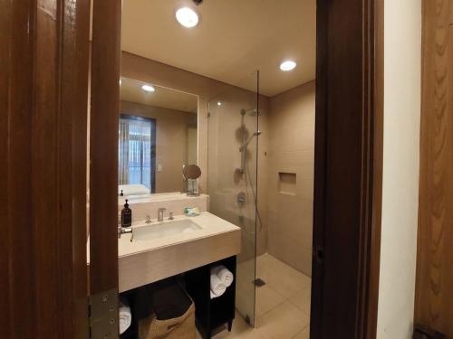 een badkamer met een wastafel, een douche en een spiegel bij Sea Breeze Verandas at Anvaya Cove Penthouse Unit with Complete Sea View in Morong
