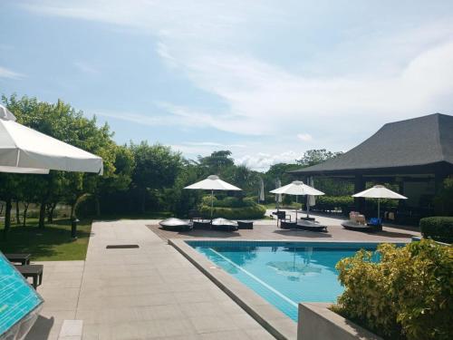 a swimming pool with chairs and umbrellas at Sea Breeze Verandas at Anvaya Cove Penthouse Unit with Complete Sea View in Morong