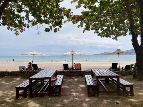 two picnic tables and umbrellas on the beach at Sea Breeze Verandas at Anvaya Cove Penthouse Unit with Complete Sea View in Morong