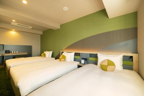 two beds in a room with green walls at OMO Kansai Airport by Hoshino Resorts in Izumi-Sano