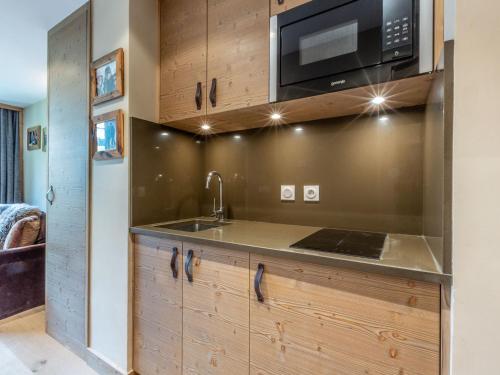 une cuisine avec un évier et un micro-ondes dans l'établissement Studio chaleureux et élégant, front de neige à Val d'Isère, proche centre et pistes - FR-1-694-190, à Val dʼIsère