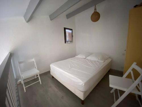 - une chambre avec un lit blanc et 2 chaises blanches dans l'établissement Appartement avec mezzanine, 4 pers, plage à 250m, parking privé, commerces à proximité - FR-1-81-43, à Port-Leucate