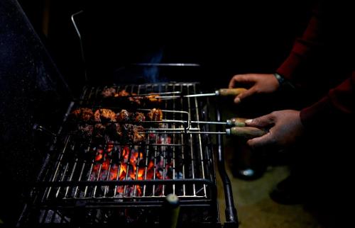 a person is cooking food on a grill at Vista Suites Doddabetta Ooty By Bestinn Leisure in Ooty