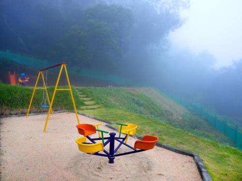 a playground with a swing set on a hill at Vista Suites Doddabetta Ooty By Bestinn Leisure in Ooty