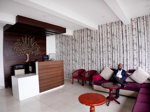 a man sitting on a couch in a living room at Vista Suites Doddabetta Ooty By Bestinn Leisure in Ooty