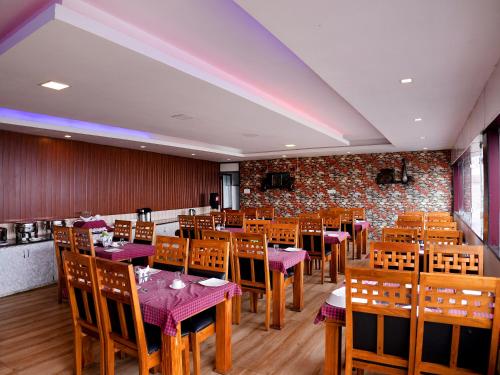 a restaurant with wooden tables and chairs and a brick wall at Vista Suites Doddabetta Ooty By Bestinn Leisure in Ooty