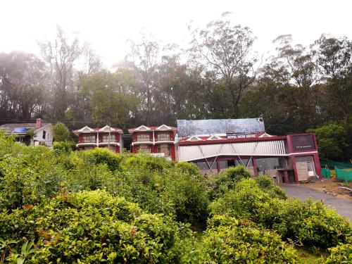 a group of houses on a hill with bushes at Vista Suites Doddabetta Ooty By Bestinn Leisure in Ooty