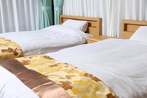 2 camas en una habitación de hotel con sábanas blancas en 那須町湯本の那須御用邸近くのログハウス, en Nasu-yumoto