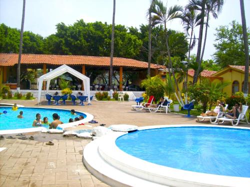 a pool at a resort with people sitting around it at Tropiclub Playa El Cuco in El Cuco