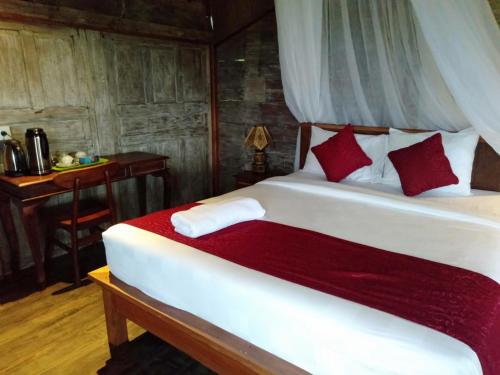a bedroom with a white bed with red pillows at D'Ume Bendoel Homestay in Jatiluwih