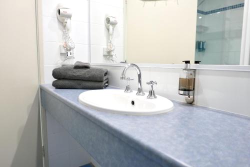 a bathroom counter with a sink and a mirror at Pelican Motor Inn in Merimbula