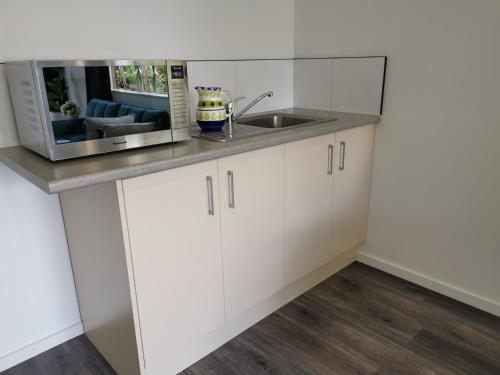 a kitchen with white cabinets and a sink at Farm Stay on Te Awa Cycleway in Tamahere