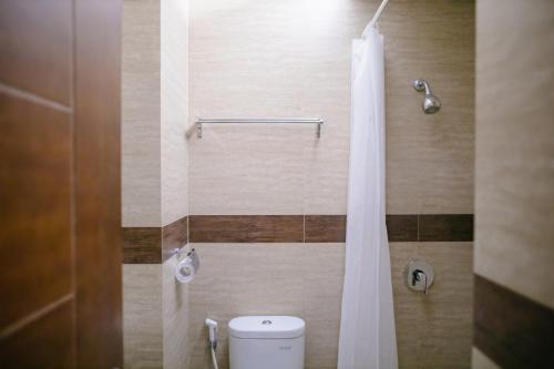 y baño con aseo y cortina de ducha. en BIZ City Center Hotel Ambon, en Ambon