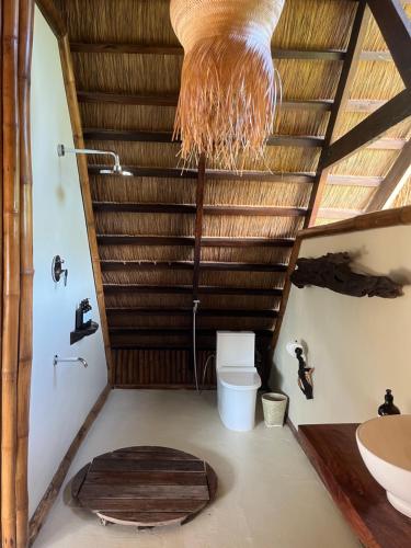 a bathroom with a toilet and a wooden ceiling at The Beach House Ocam Ocam in Busuanga