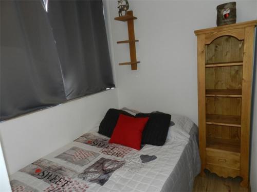 - une petite chambre avec un lit et un oreiller rouge dans l'établissement Appartement rénové Val Thorens - 4 pers, cheminée, skis aux pieds, proche commerces/restaurants - FR-1-637-54, à Val Thorens