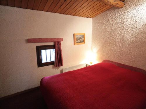 - une chambre avec un lit rouge et une fenêtre dans l'établissement Duplex rustique avec grande terrasse au Sud, proche vieux Val-d'Isère - FR-1-694-310, à Val dʼIsère