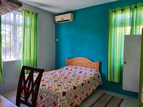 a bedroom with a bed with blue walls and green curtains at 3 bedrooms apartement at Pamplemousses 800 m away from the beach with private pool enclosed garden and wifi in Pamplemousses Village