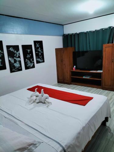 a bedroom with a white bed with a tv on it at Mope Beach Resort in San Narciso