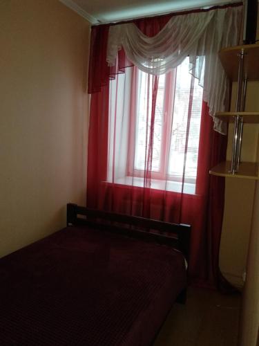 a bedroom with a window with red curtains at 2-x Apartments Center Wi-Fi около Площади in Chernihiv