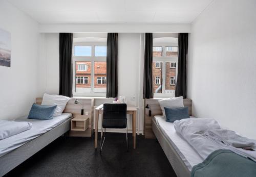 a room with two beds and a desk and two windows at Hotel Ansgar in Esbjerg