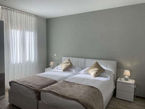 1 dormitorio con 1 cama blanca grande y 2 almohadas en Albergo Stazione, en Roveredo