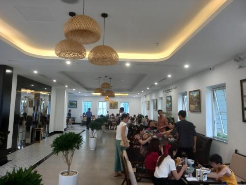 a group of people sitting in a room with a restaurant at INDOTEL HALONG HOTEL in Ha Long