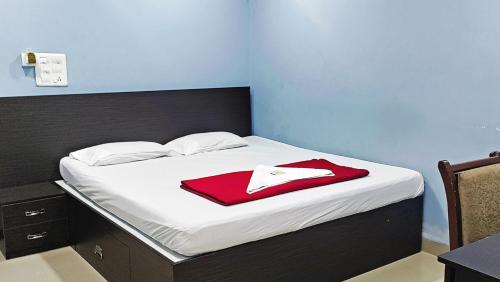 a bed with a red blanket on top of it at STAYMAKER Hotel Keerthi in Māvalli