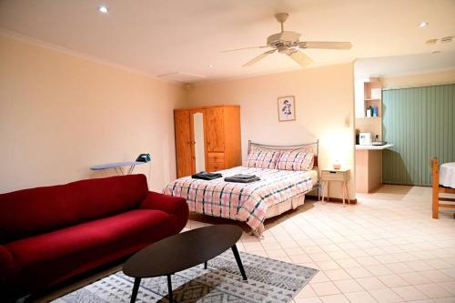 a living room with a red couch and a bed at Spacious studio in AliceSprings QueenBed+KSAirbed in Alice Springs