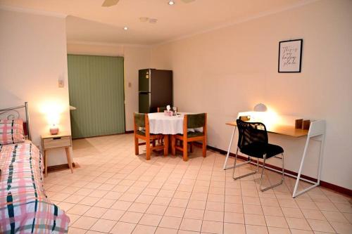 a room with a table and chairs and a kitchen at Spacious studio in AliceSprings QueenBed+KSAirbed in Alice Springs