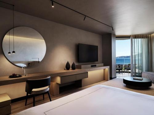 sypialnia z dużym lustrem i telewizorem w obiekcie Ammades All Suites Beach Hotel - Adults Only w mieście Faliraki