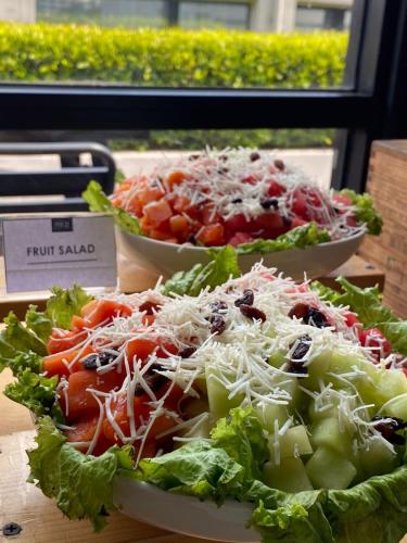 two plates of food on a table with salad at Neo Hotel Puri Indah in Jakarta