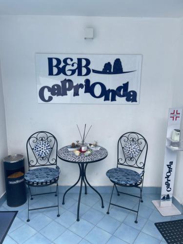 une table et deux chaises avec une table et un panneau dans l'établissement CapriOnda, à Capri