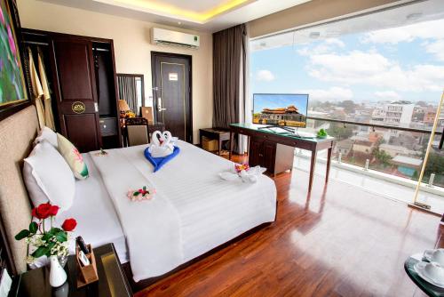 a hotel room with a bed and a desk and a window at Thanh Lich Hue Hotel in Hue