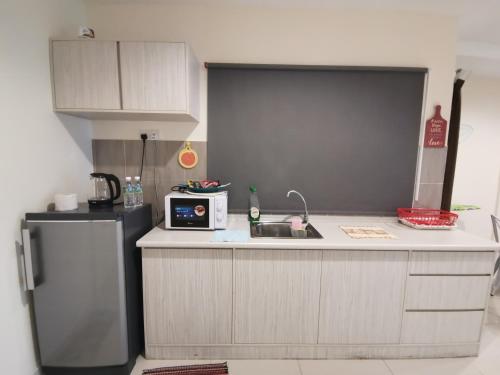 a kitchen with a refrigerator and a microwave at Peaceful 1-bedroom unit at Marina Island by JoMy Homestay in Lumut