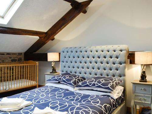 a bedroom with a blue tufted bed and two lamps at Doddick Chase Cottage - Uk1363 in Threlkeld