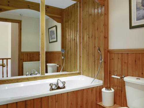a bathroom with a tub and a toilet and a mirror at Doddick Chase Cottage - Uk1363 in Threlkeld