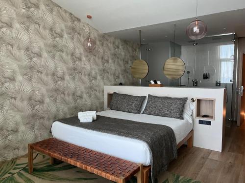 a bedroom with a bed with a bench and pendant lights at Playa Grande by Tropical - Adults Only in Gavà