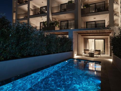 a swimming pool in front of a building at night at Ammades All Suites Beach Hotel & Spa - Adults Only in Faliraki