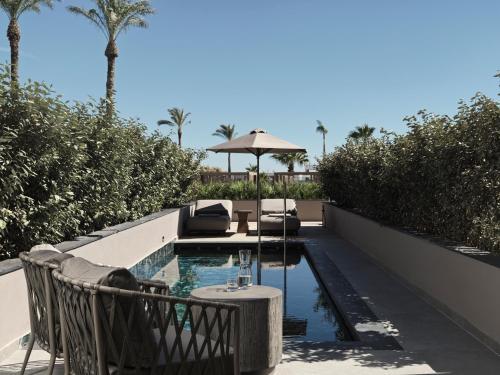 a swimming pool with chairs and an umbrella on a patio at Ammades All Suites Beach Hotel - Adults Only in Faliraki