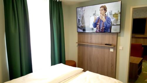 a hotel room with a tv and a bed at Hotel & Restaurant Hubertus Sehnde in Sehnde