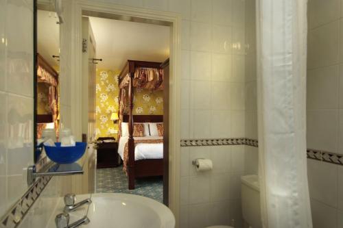 a bathroom with a sink and a toilet and a bedroom at Best Western Kilima Hotel in York