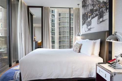 a bedroom with a white bed and a large window at Hotel Indigo Bangkok Wireless Road by IHG in Bangkok